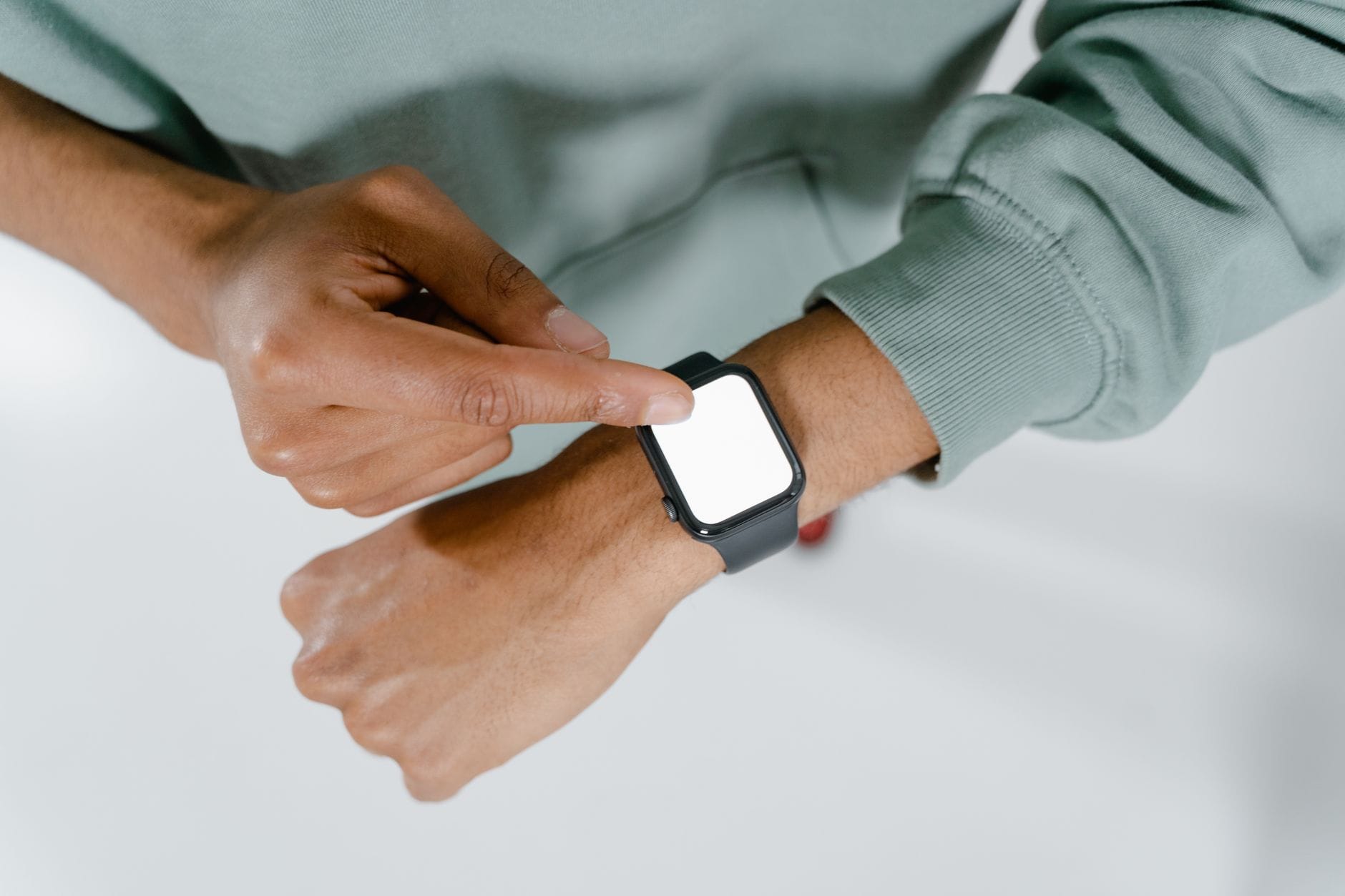 Osoba w zielonym swetrze obsługuje smartwatch na nadgarstku