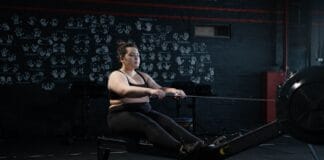 Kobieta plus size ćwicząca na wioślarzu w domu