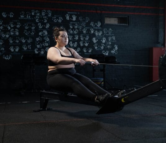 Trening obwodowy cardio dla osób z dużą nadwagą – zestaw bezpieczny dla kolan Kobieta plus size ćwicząca na wioślarzu w domu