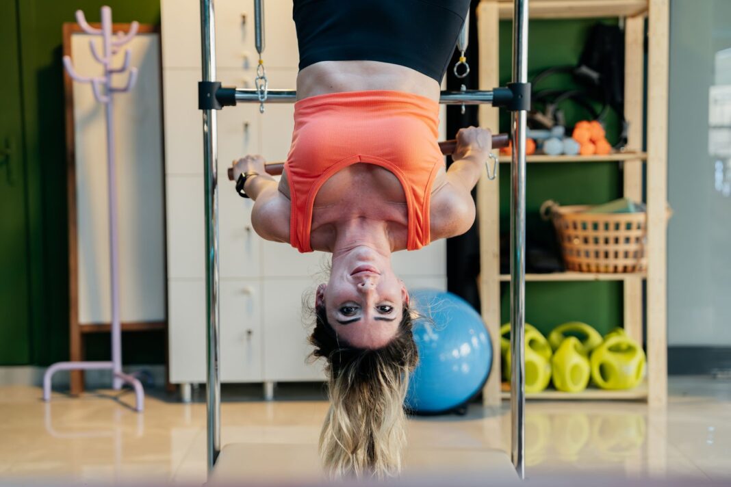Kobieta wykonująca odwrócone ćwiczenie Pilates na reformerze w siłowni